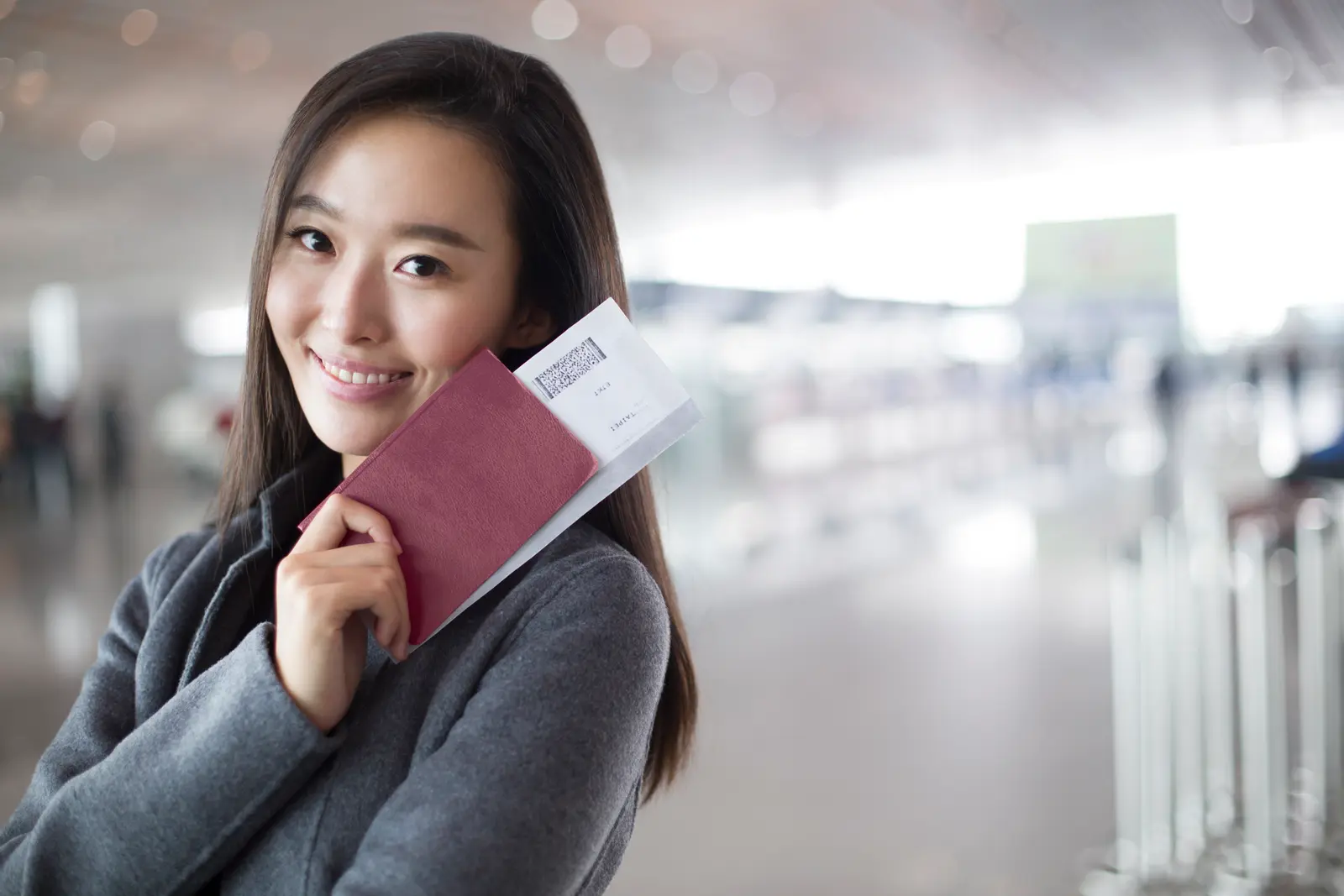 ผู้เดินทางยิ้มถือหนังสือเดินทางและตั๋วที่สนามบิน
